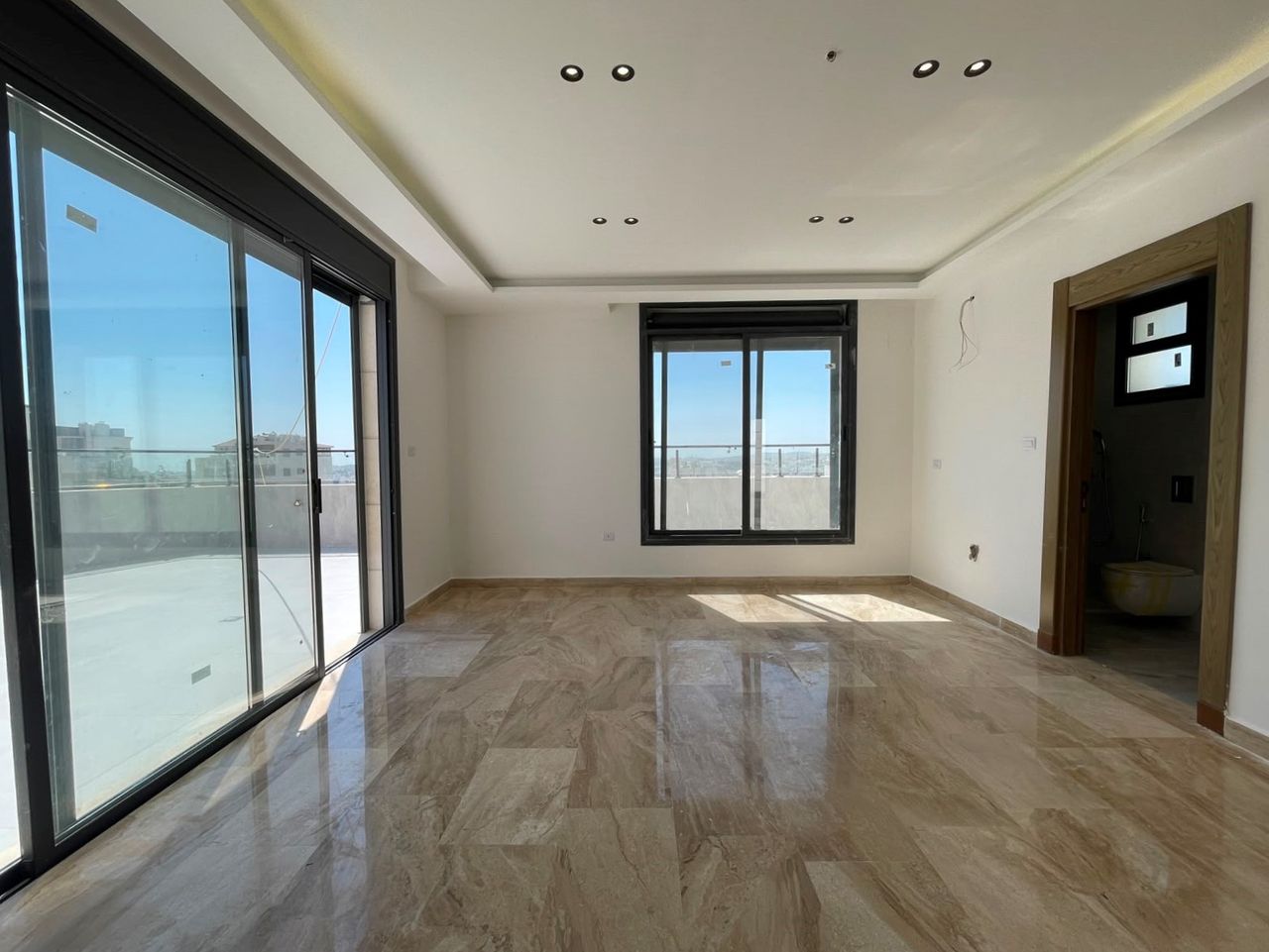 An empty reception with full-height sliding doors onto a terrace and a second window to the side.