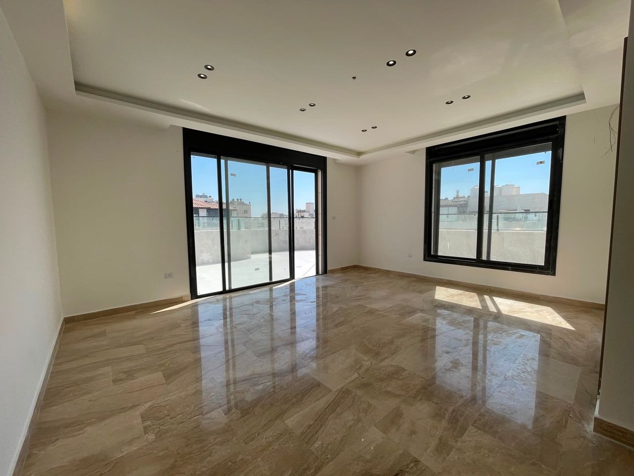 An empty reception lit from two sides, with sliding doors onto a balcony.